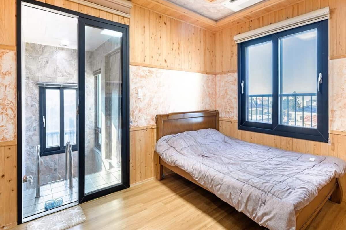 A room with a bed, a sliding glass door, and a window.