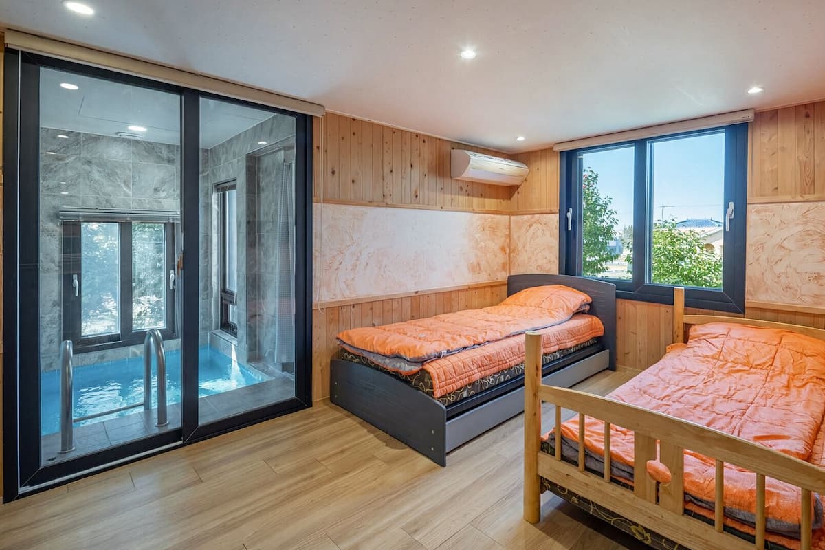 A bedroom with two beds, a sliding glass door to a balcony, and a large window.