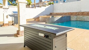 Ein Poolbereich mit integriertem Wasserspiel, Grill und Hinweisschild für die Ruhezeiten.