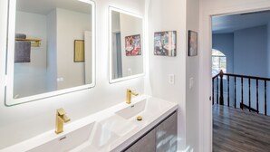 Ein modernes Badezimmer mit zwei Waschbecken, großen Spiegeln und Bildern an den Wänden.