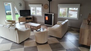 A living room with a fireplace, sofas, a TV, and a wooden cabinet. - Charming, bright, spacious house (sleeps 12) 2 mns from the beach (Locquirec)