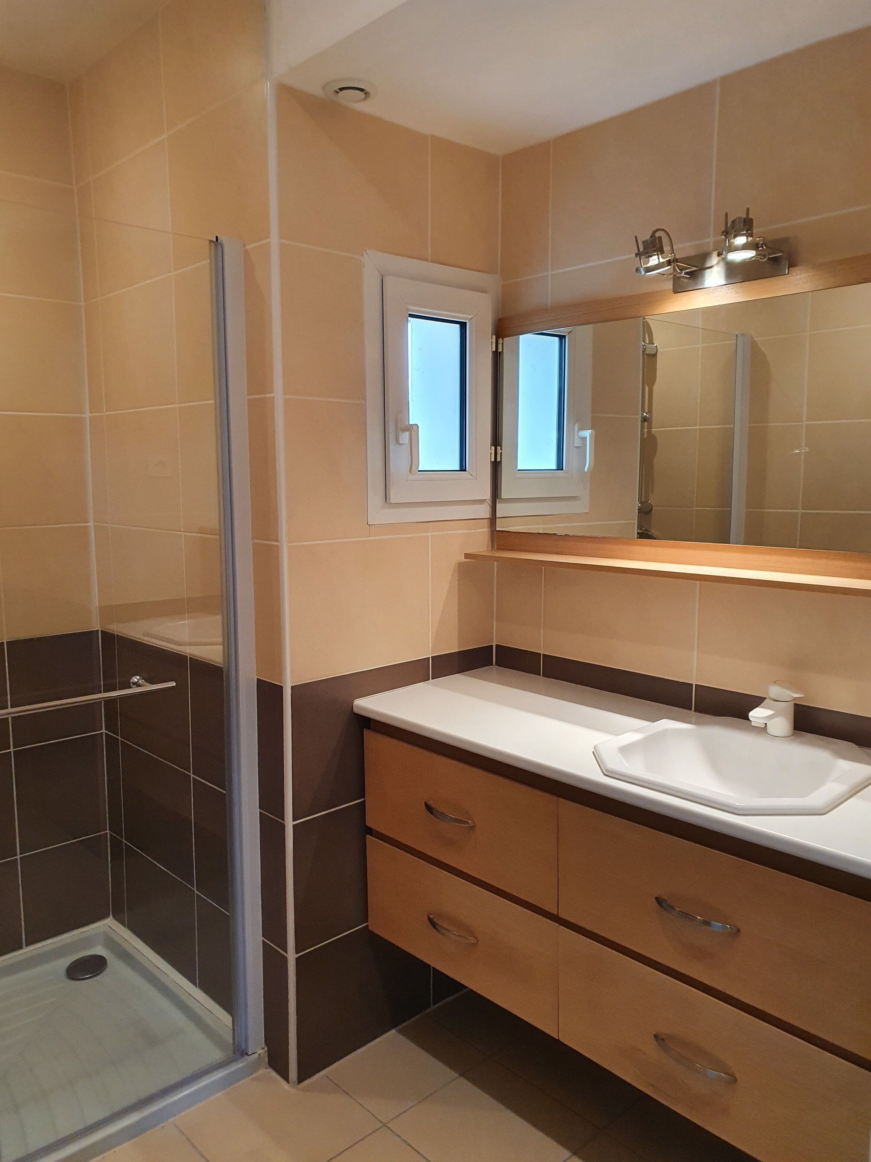 Een moderne badkamer met een douchecabine van glas, een wit wastafelmeubel en een spiegel erboven.