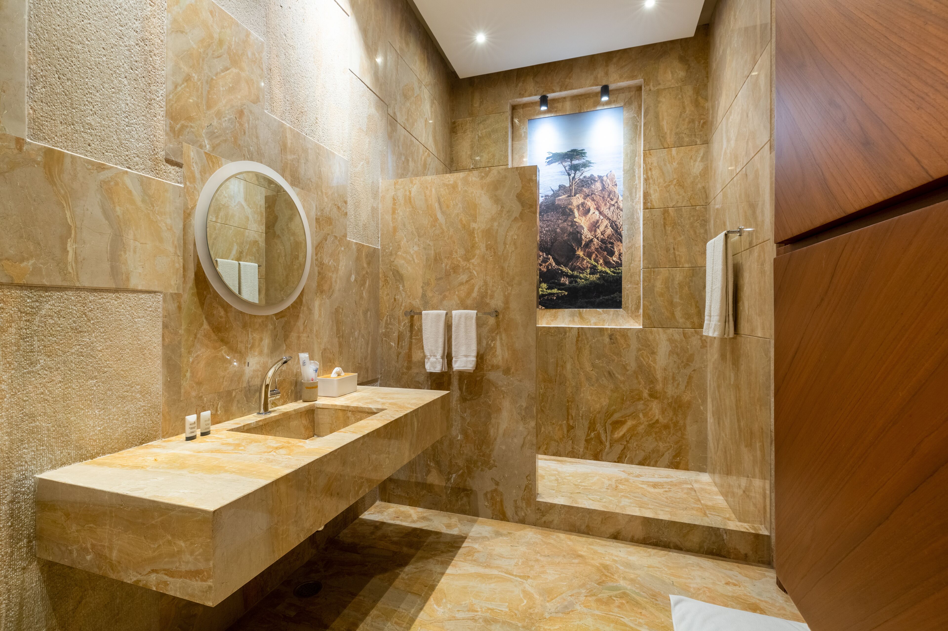 Un baño moderno con un lavamanos grande, un espejo y una zona de ducha.
