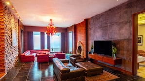 Een moderne woonkamer met leren banken, een open haard, een grote televisie en een stenen muur.