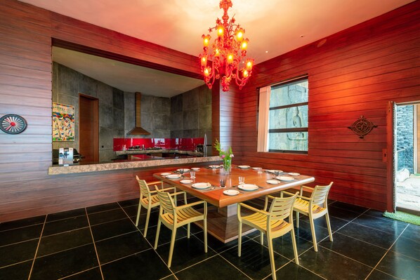 A modern kitchen with a central island, wooden paneling, and a chandelier.