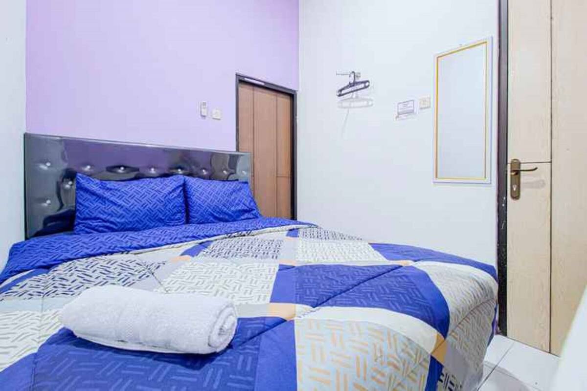 Ein Schlafzimmer mit einem Bett, einer Holztür und einem an der Wand befestigten Handtuchhalter.