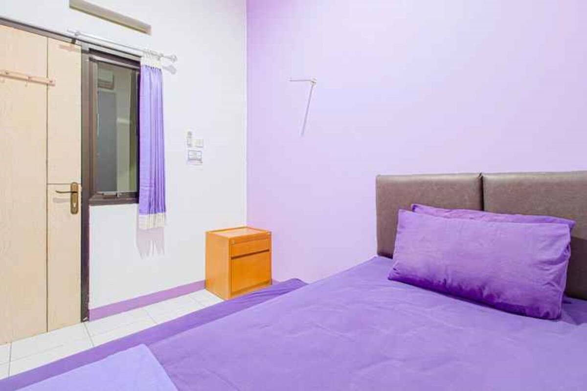 Ein Schlafzimmer mit Bett, Nachttisch, Kleiderschrank und einem Fenster mit Vorhängen.