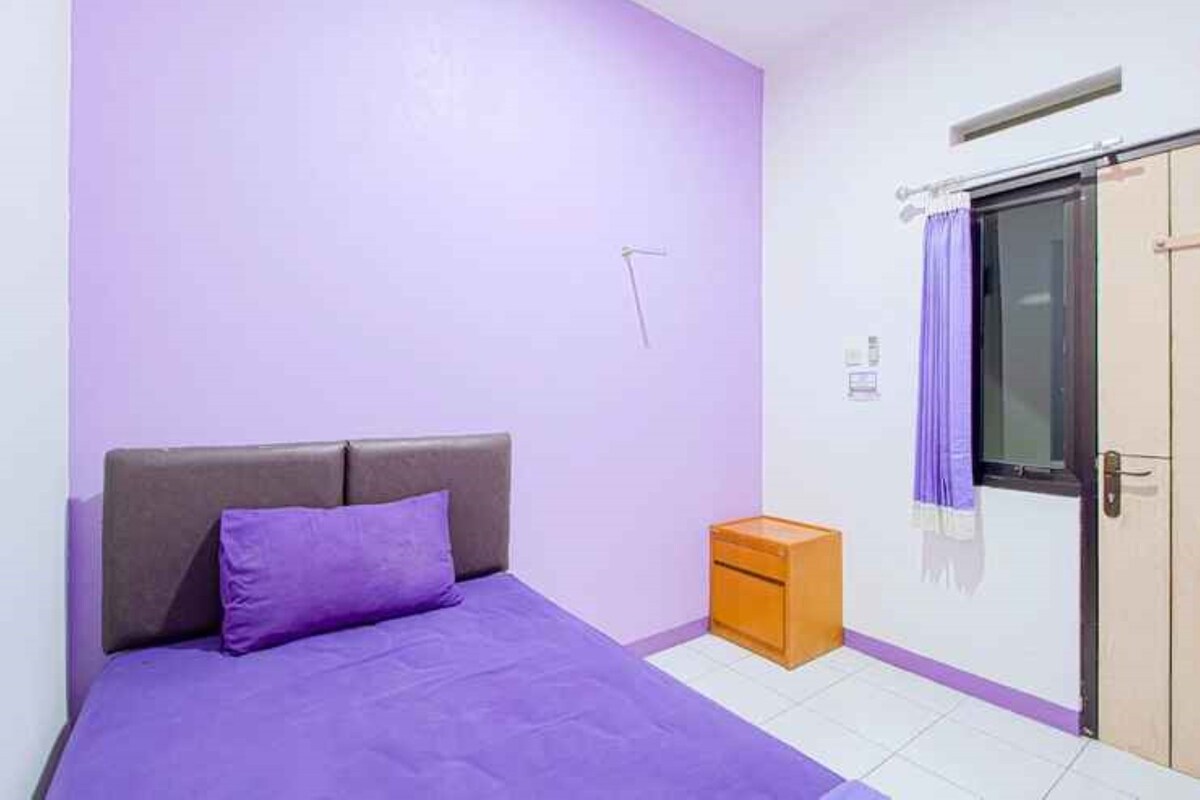A bedroom with a bed, a nightstand, a window with curtains, and a door.