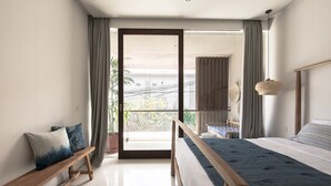 Ein modernes Schlafzimmer mit einem großen Bett, einer Holzbank und Blick ins Freie.