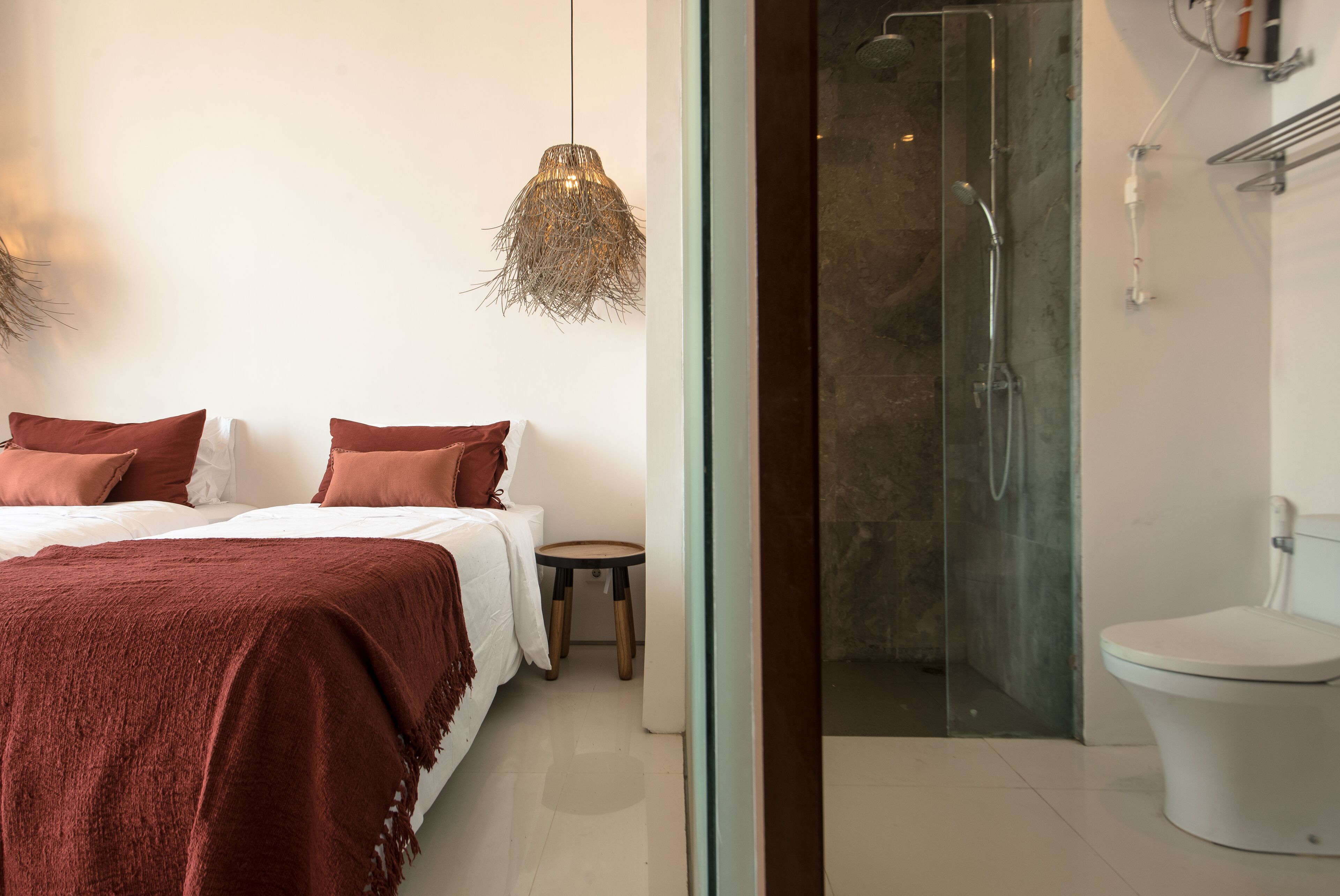 Quarto moderno com uma cama grande, mesa de cabeceira e luminária pendente.