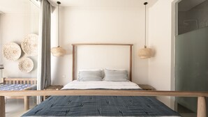 Ein modernes Schlafzimmer mit einem Holzbettgestell, zwei hängenden Rattanlampen und einem großen Fenster mit transparenten Vorhängen.