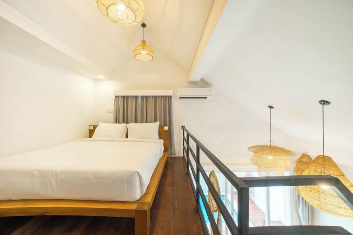 A hotel room with a bed, a balcony, and hanging lamps.