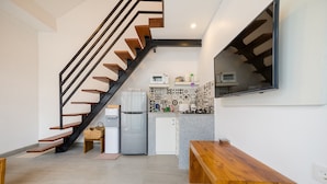 Une cuisine moderne avec un escalier en bois, un four à micro-ondes encastré et un petit réfrigérateur.