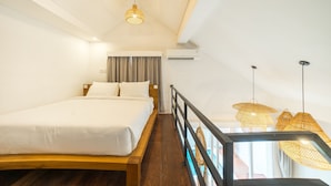 Une chambre avec un lit en bois, un balcon agrémenté de lampes en osier et une vue sur l’extérieur.