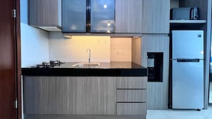 A modern kitchen with a black countertop, stainless steel sink, and a built-in refrigerator. - U Residence 2 by Ana Room (Curug)