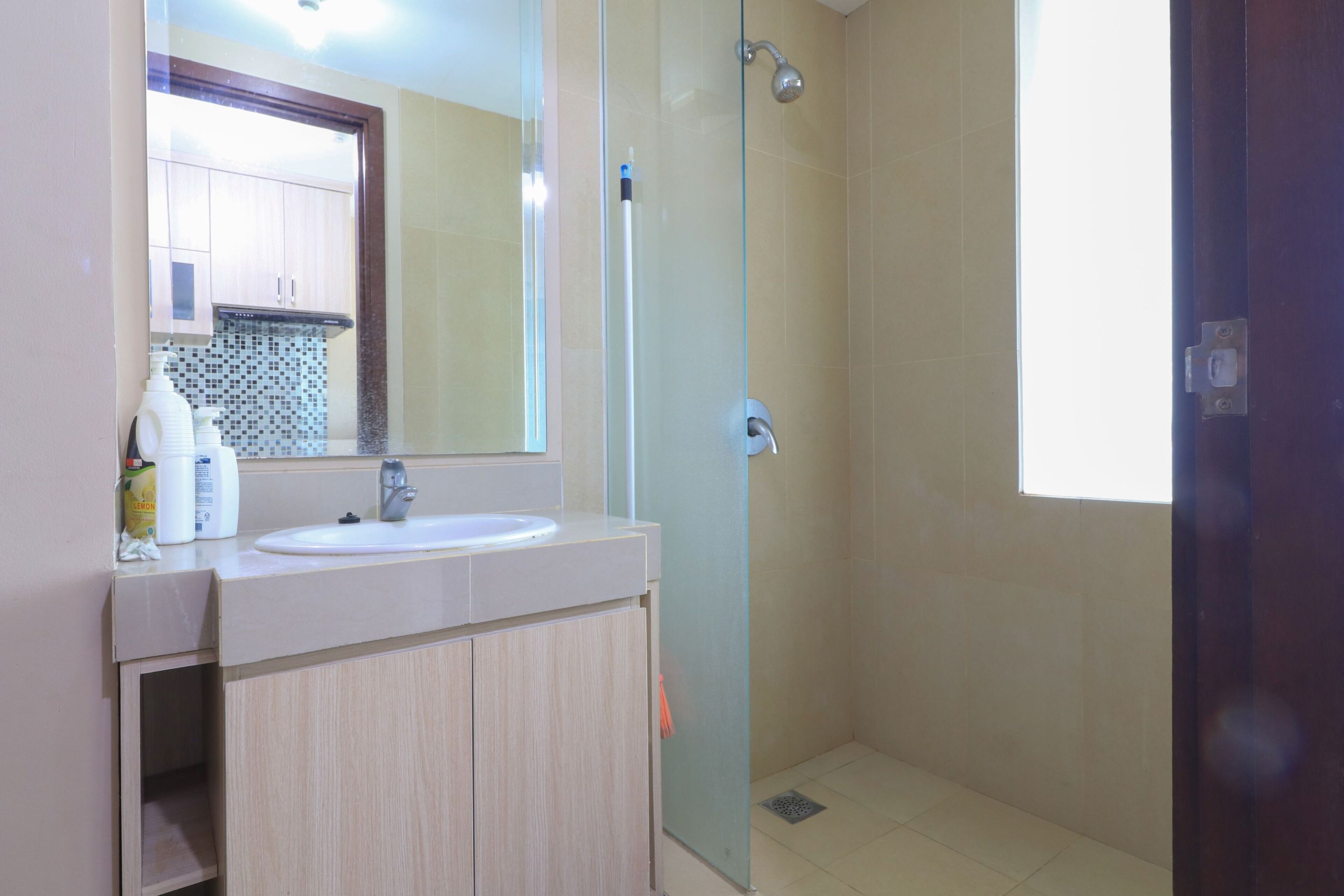 A bathroom with a glass-enclosed shower, a sink with a mirror above it, and a cabinet below.