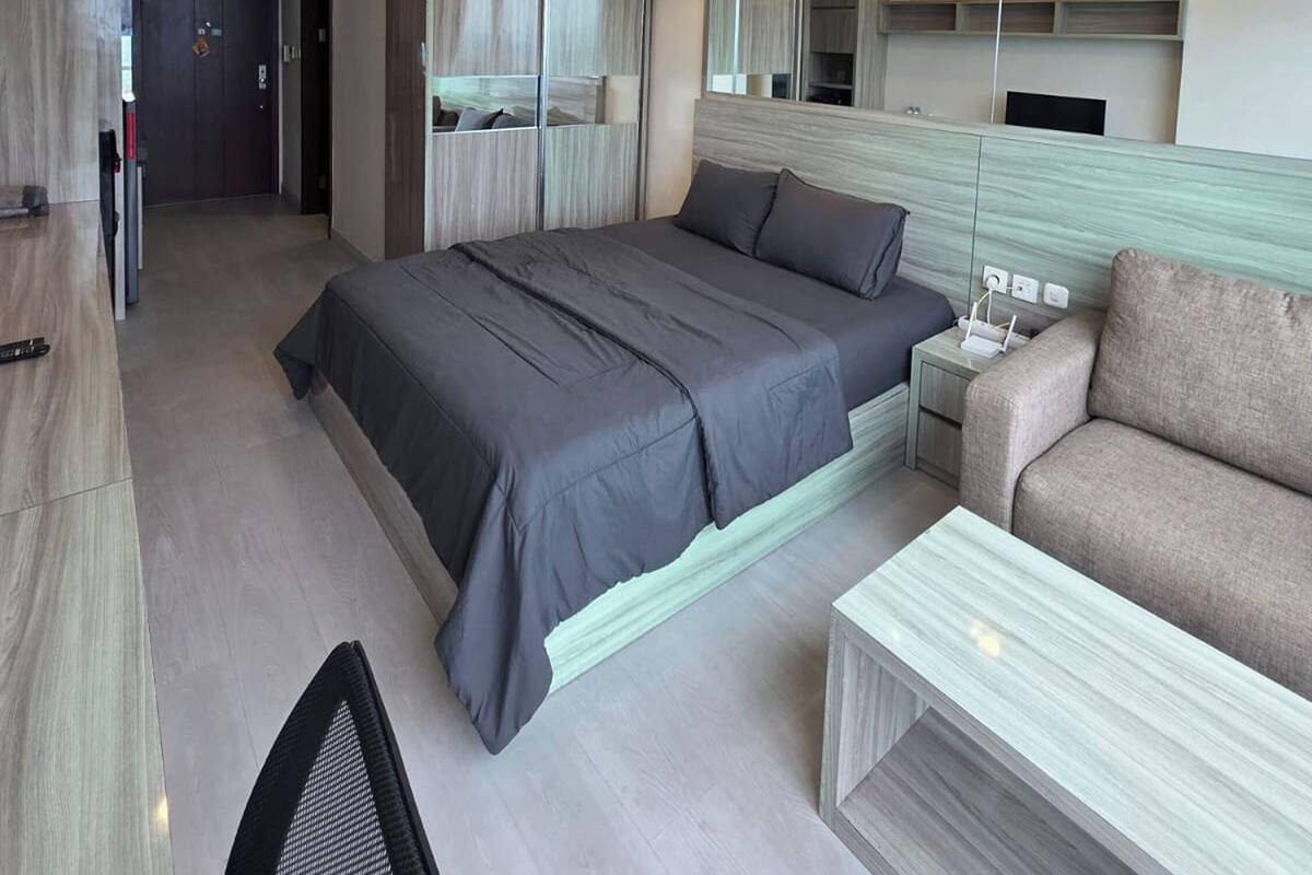 Ein modernes Hotelzimmer mit einem großen Bett, einer Couch, einem Schreibtisch und einem Spiegel.