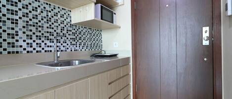 A modern kitchen with a sink, a microwave, and a wooden door.