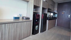 A modern kitchen with wooden cabinetry, a built-in water dispenser, and a refrigerator. - U Residence 2 by Ana Room (Curug)