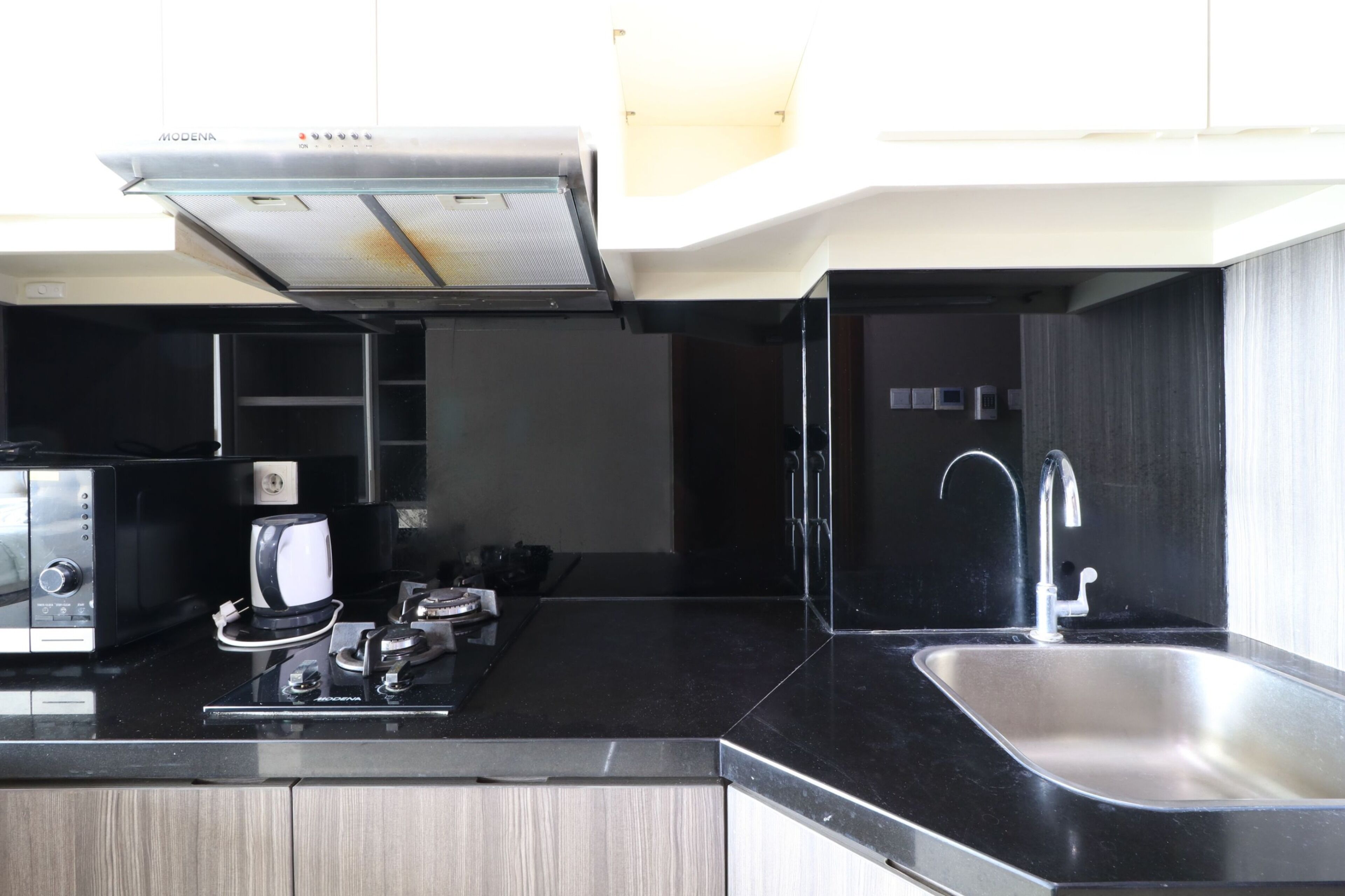 A compact kitchen with a modern design, featuring a built-in microwave, a coffee maker, and a stainless steel sink.
