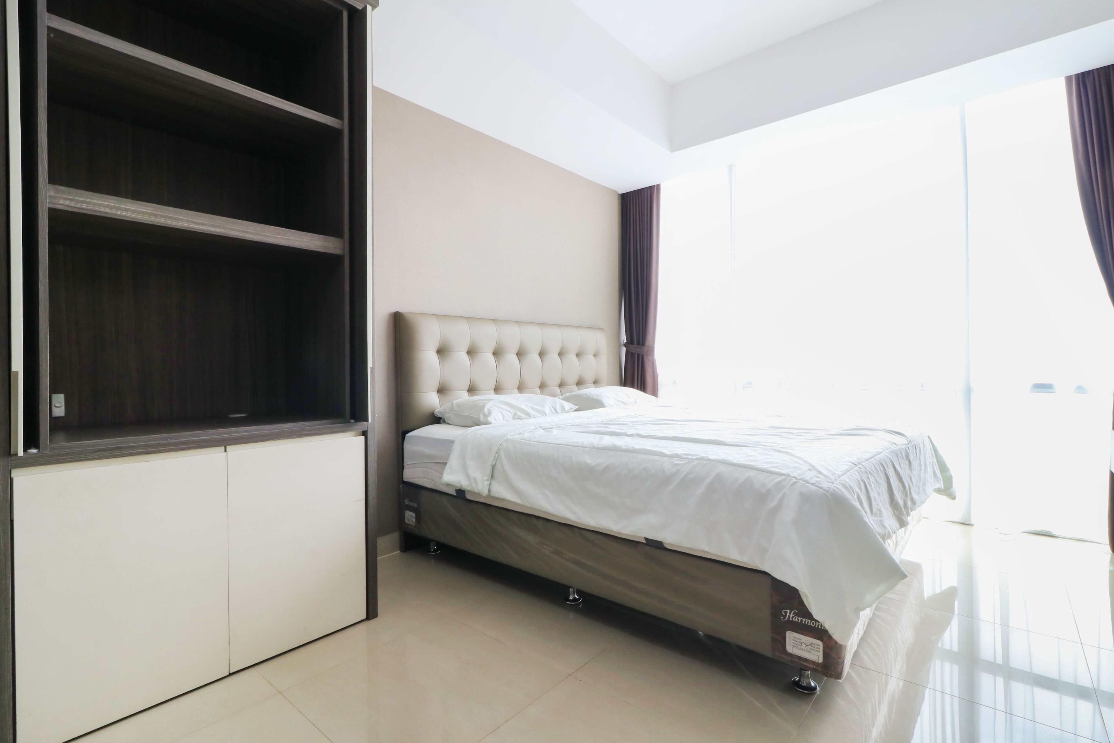 A modern bedroom with a large bed, built-in wardrobe, and a large window.