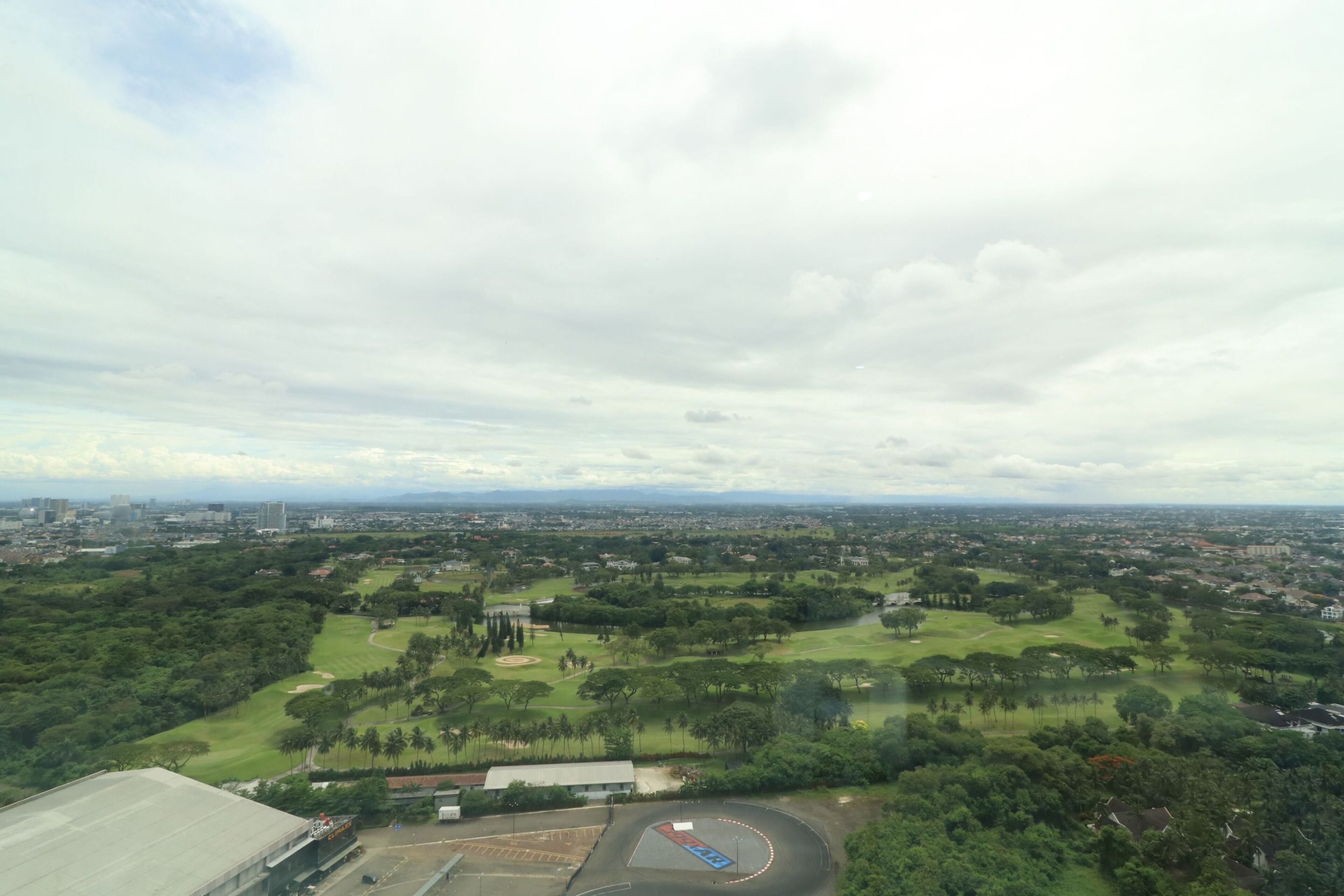 An aerial view of a golf course with a cityscape in the background.