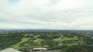 An aerial view of a golf course with a cityscape in the background.