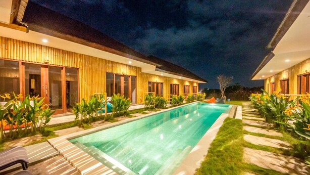 A modern hotel with a swimming pool, outdoor seating, and a well-lit facade. - Boku Boku (Pererenan)
