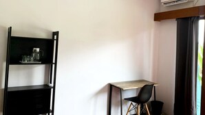 A room with a desk, two chairs, a black shelving unit, and an air conditioning unit. - Boku Boku (Pererenan)