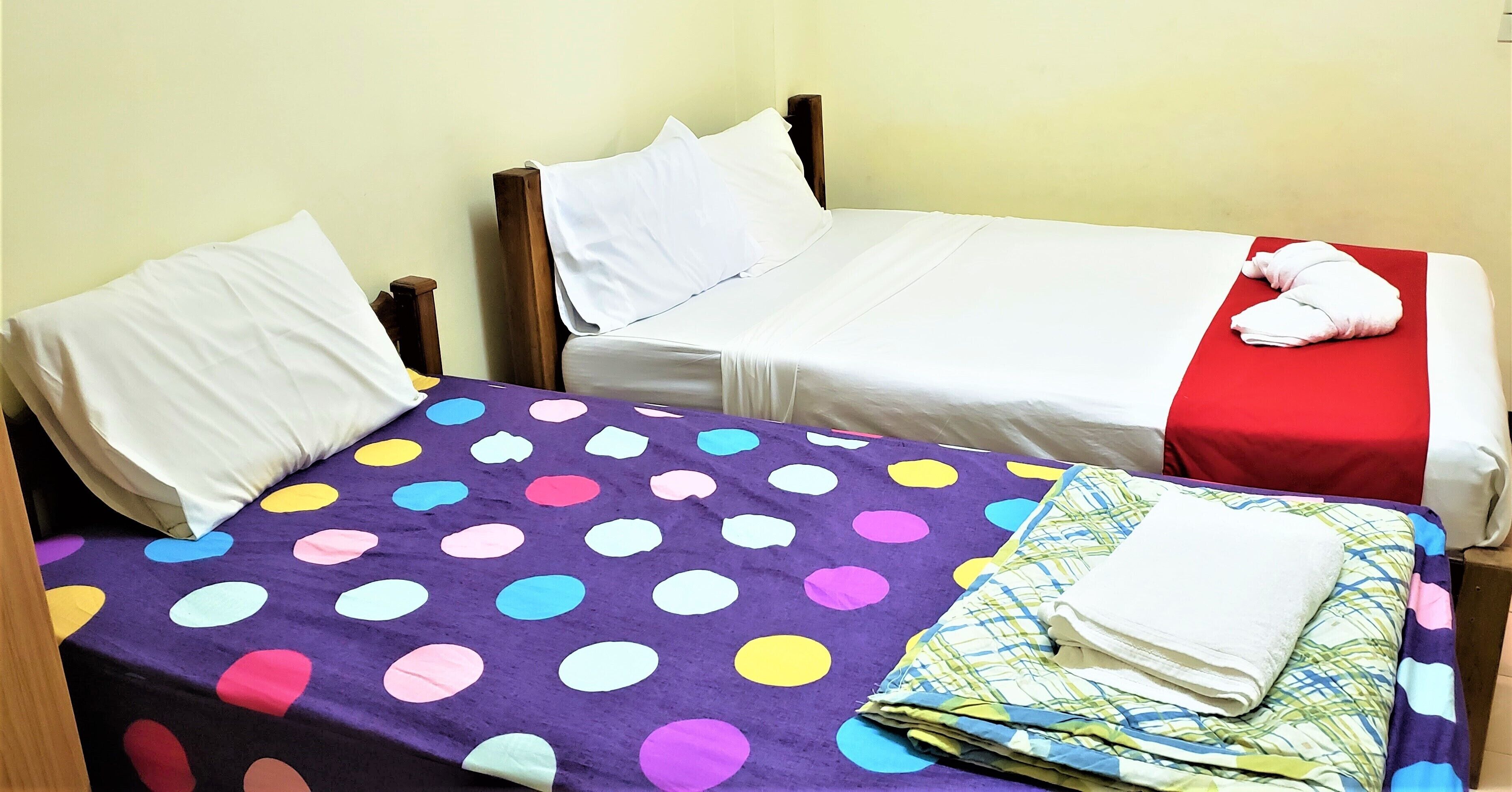 A room with two beds, each with a different colored bedspread.