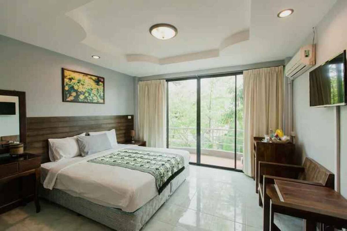 A hotel room with a bed, a desk, a chair, a TV, and a large window.