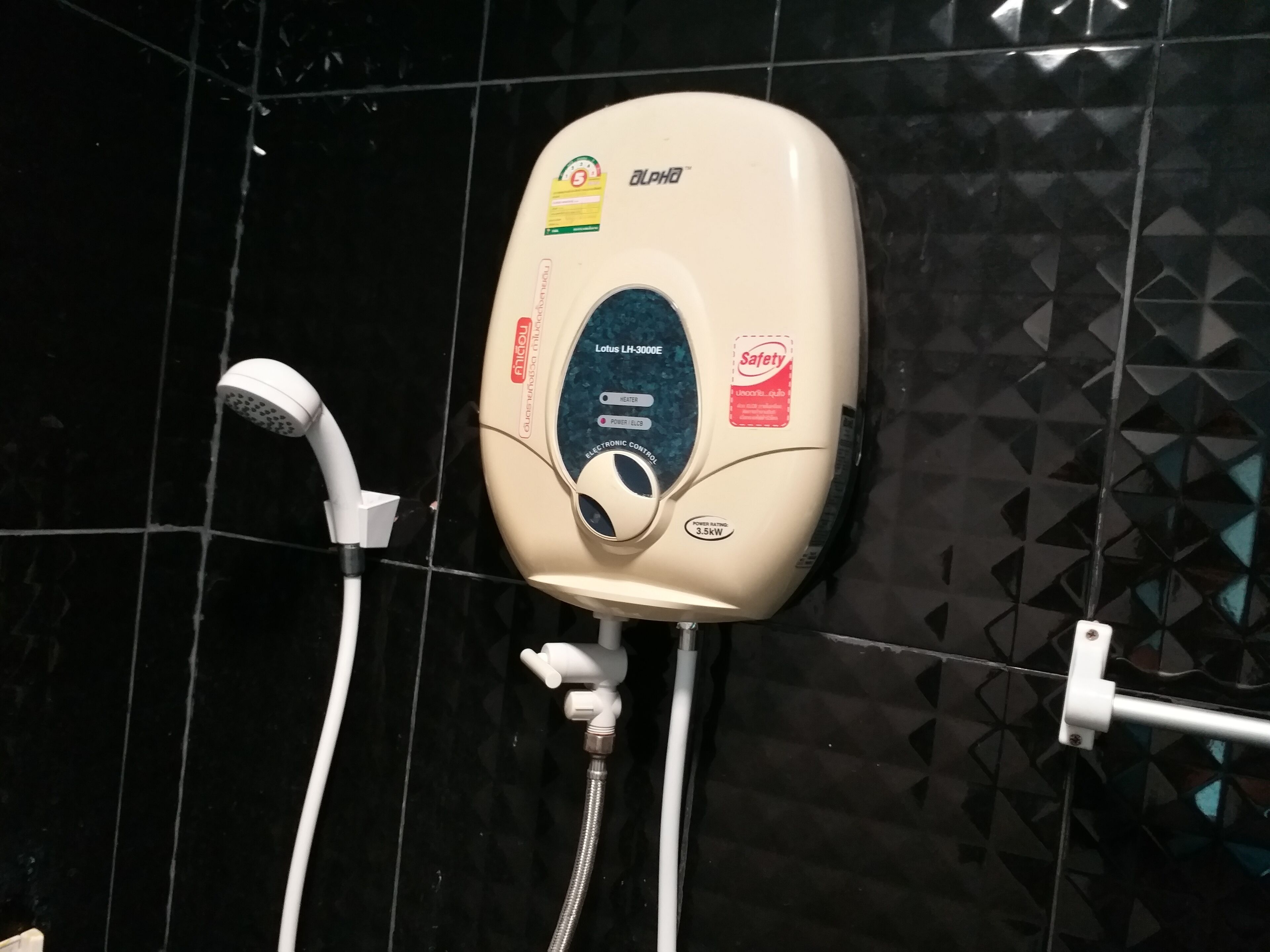 A wall-mounted shower unit with a handheld showerhead and a handheld faucet.