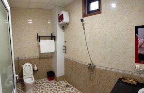 Un baño con inodoro, ducha, toallero y un lavamanos pequeño.