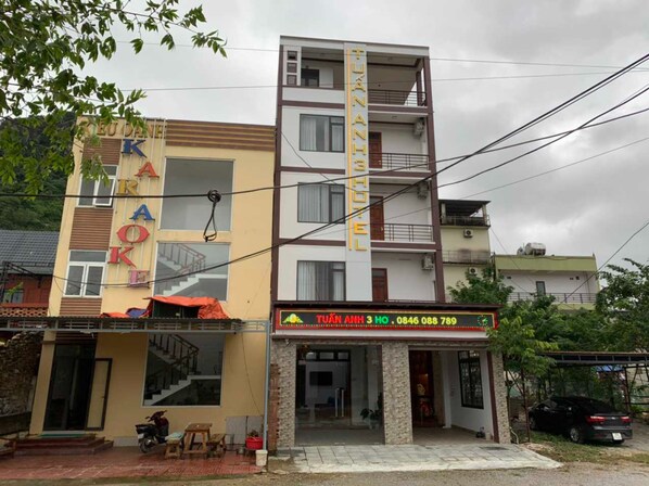 Un hotel con un cartel que dice "TUAN ANH HOTEL" y un número de contacto.