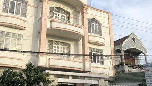Un hotel con un letrero llamativo, varios balcones y una entrada protegida por una reja.