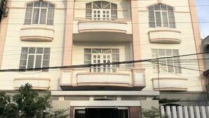 Un hotel con un letrero llamativo que dice "HOTEL THANH DAT". Presenta una fachada simétrica con numerosas ventanas y balcones.