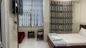 Hotelkamer met een bed, een aan de muur bevestigde televisie, een klein tafeltje, een stoel en een rode bank.