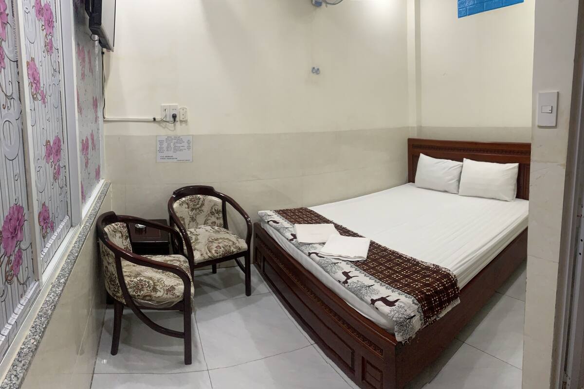 Une chambre à coucher avec un lit, deux chaises et une petite table.