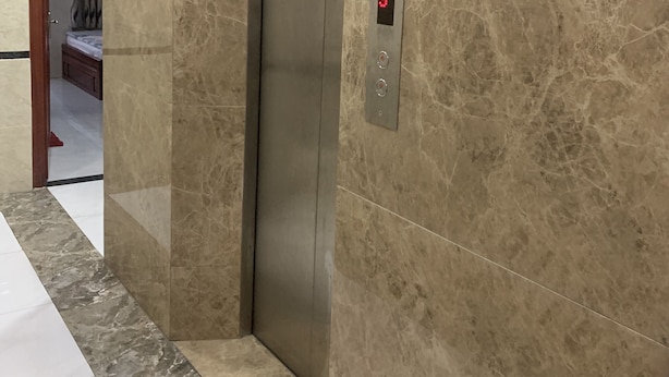Een lift met een digitaal display en een marmeren wand.