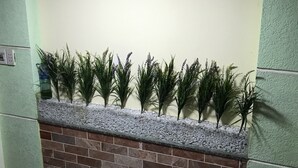Une pièce avec un sol carrelé, un mur en briques et une rangée de plantes vertes disposées sur une étagère.