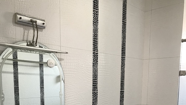 A bathroom with a white sink, a mirror, and a toilet. There is a shelf with toiletries and a shower control panel above the mirror. - Hoang Nam Hotel Hcm (Ho Chi Minh City)