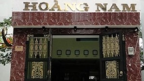 L’entrée de l’hôtel Hoàng Nam, avec sa façade en marbre et une enseigne indiquant son nom.