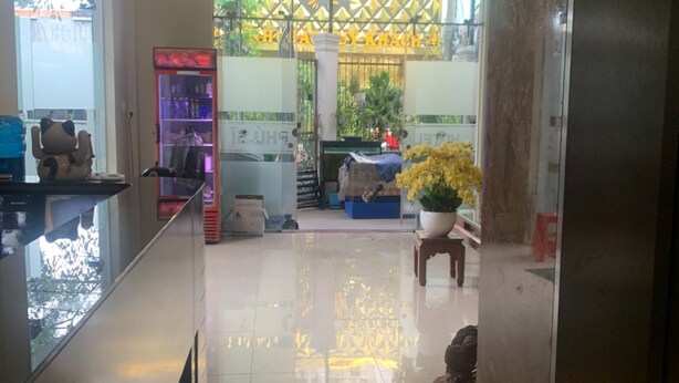 A hotel corridor with a shiny tiled floor, a reception desk, and a decorative plant. - Phu Si Hotel (Ho Chi Minh City)