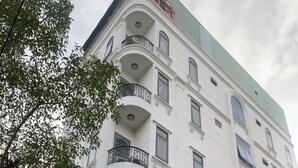 A multi-story hotel with balconies, a green roof, and a sign indicating it is a hotel. - Phu Si Hotel (Ho Chi Minh City)