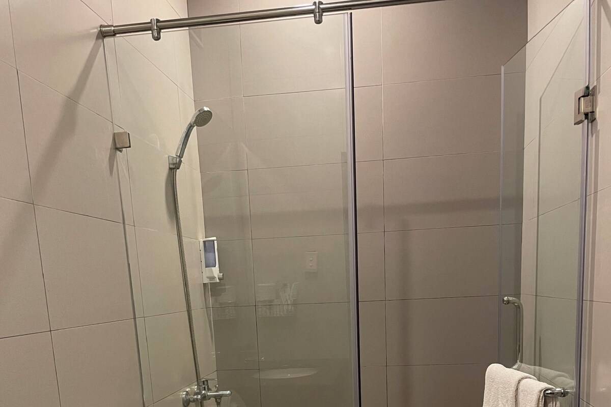 Uma casa de banho moderna com chuveiro em cabine de vidro, sanita e lavatório.