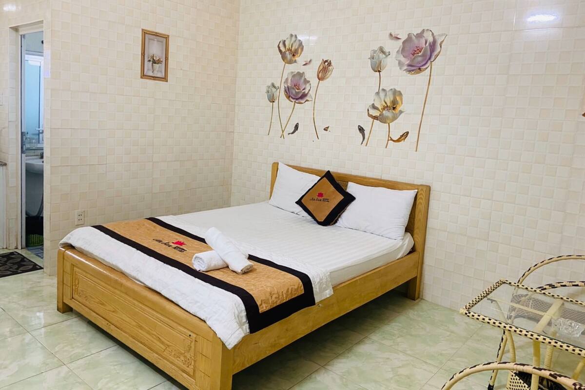A neatly made bed with a wooden frame, a white mattress, and a decorative pillow.