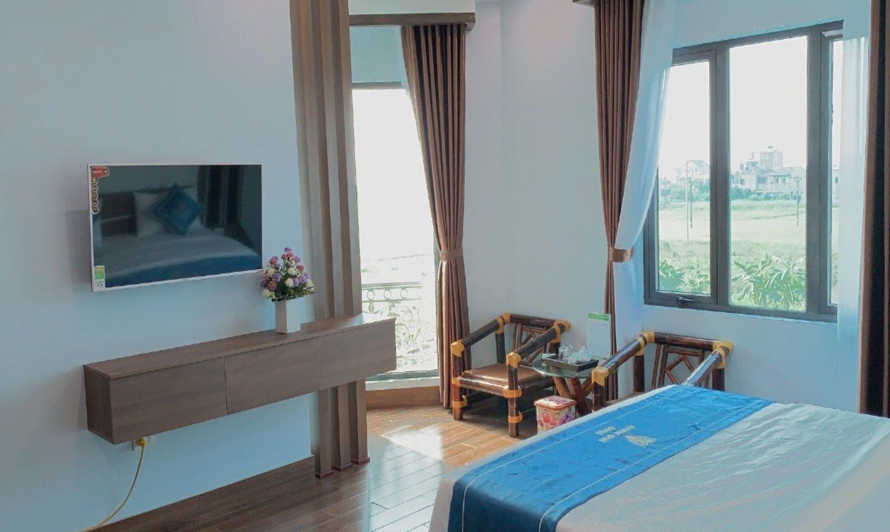 Een hotelkamer met een bed, een aan de muur bevestigde televisie, een klein tafeltje met een stoel, en een raam met uitzicht op de omgeving.