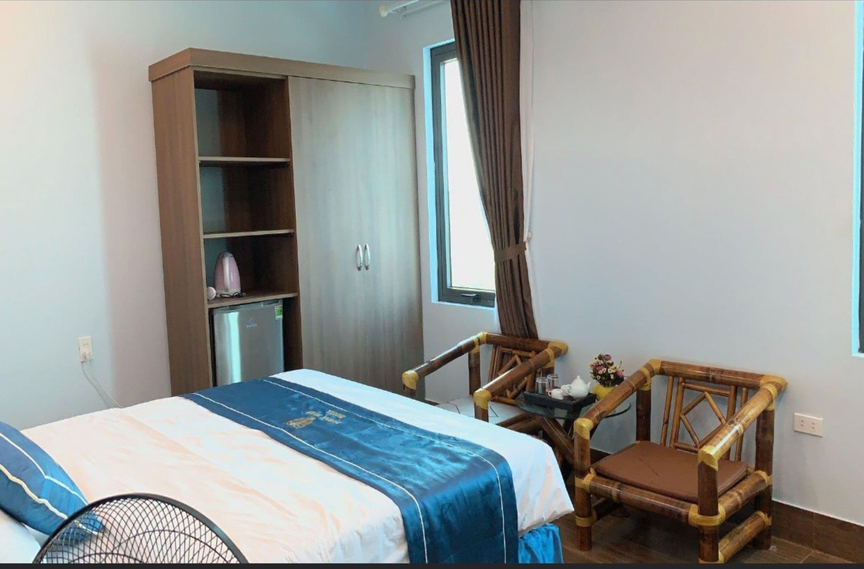 Et soveværelse med seng, garderobe, stol og lille bord.