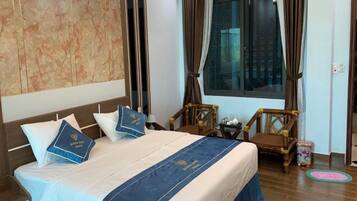 A hotel room with a bed, a wooden chair, a window, and a wall with a marble-like pattern.