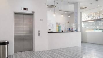 Un moderno vestíbulo de hotel con piso de mármol, una recepción y un ascensor.